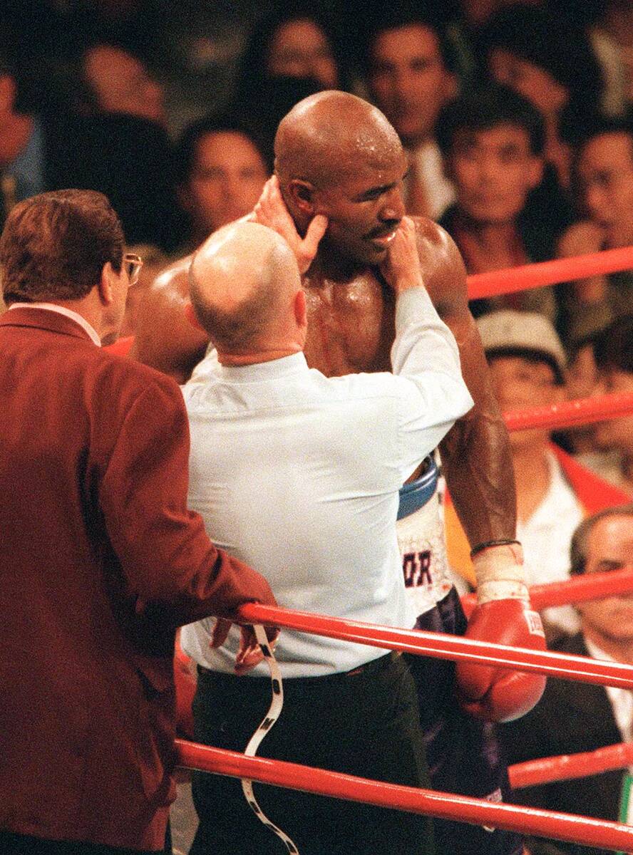 Referee Mills Lane checks out the ear of boxer Evander Holyfield after Mike Tyson bit him durin ...