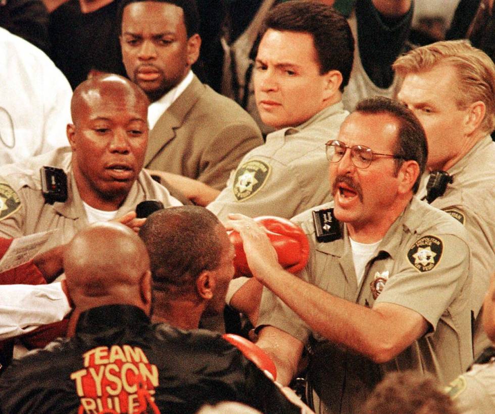 Mike Tyson scuffles with metro officers in the ring after being disqualified for biting Evander ...