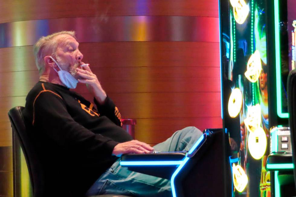 A man smokes while playing a slot machine at the Ocean Casino Resort in Atlantic City, N.J., on ...