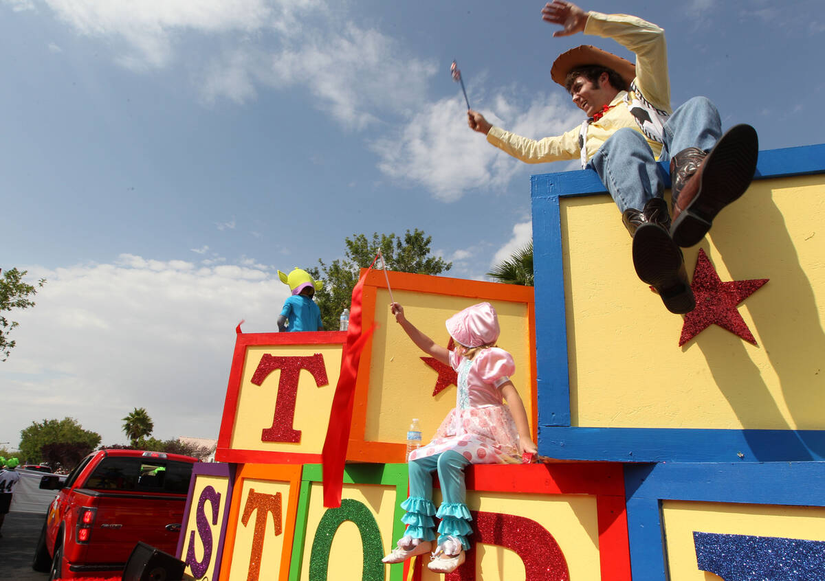 Volunteers portraying characters from Pixar's "Toy Story" wave to watchers from a float, sponso ...
