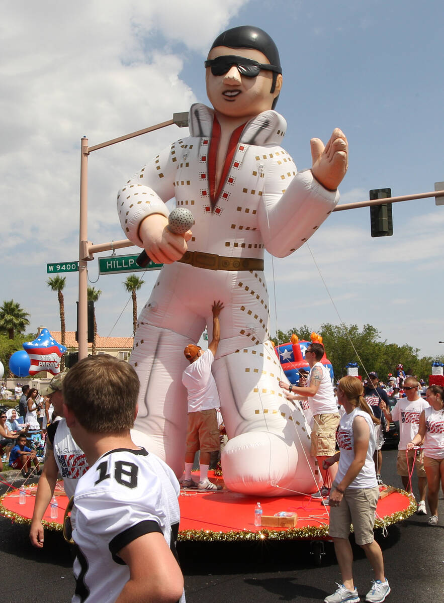 A volunteer adjusts an Elvis balloon on a float sponsored by Current Events, at the 2012 Summer ...