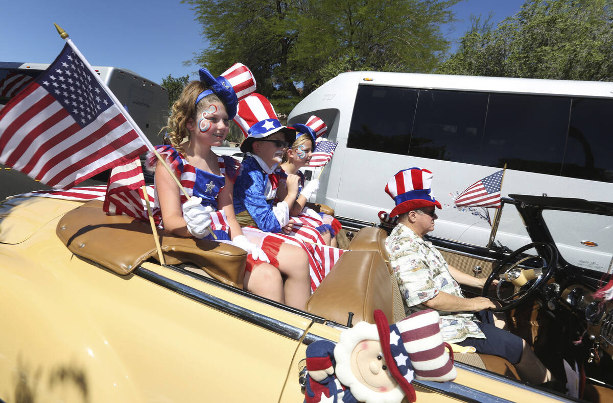 Parade goers wave to spectators in the crowd during the 2019 Summerlin Council Patriotic Parade ...
