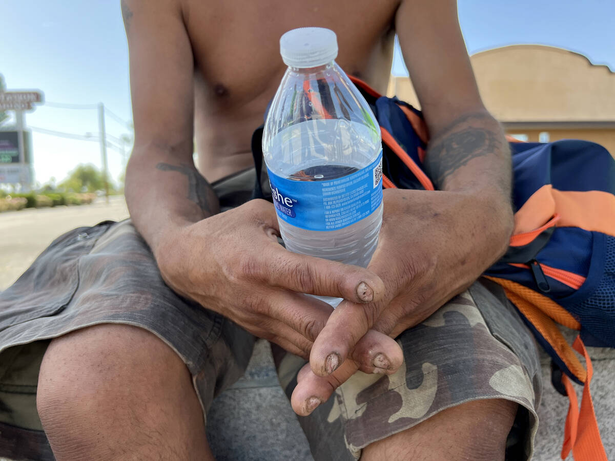 Carlos Lucero, 45, clutches a plastic water bottle he received from HELP of Southern Nevada on ...