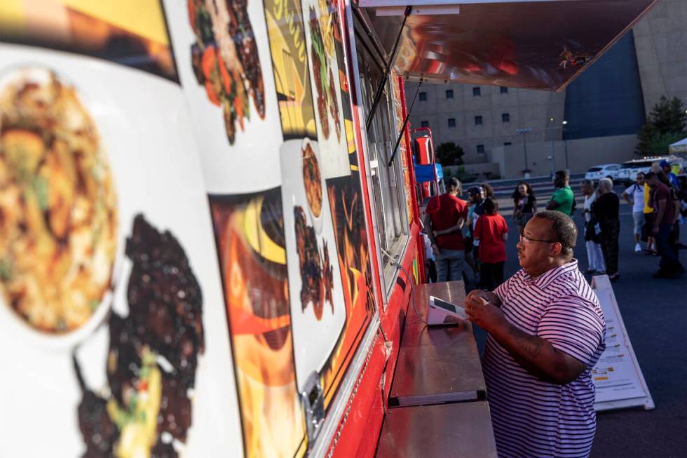 Patrons wait in line for food vendors, including at Braise & Grill Caribbean Fusion, during ...