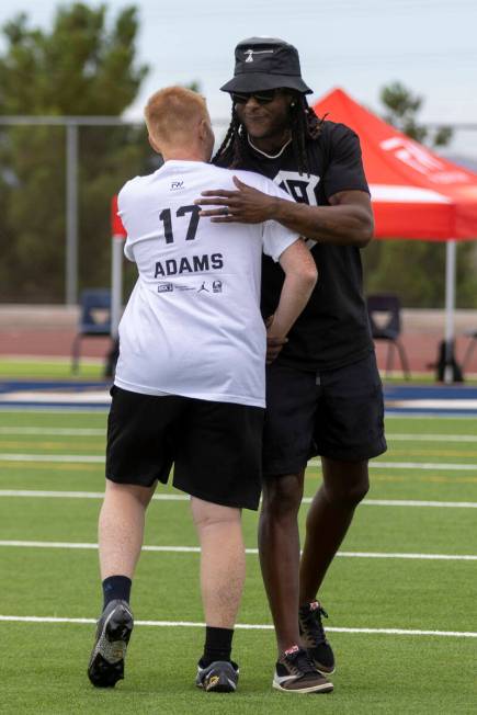Raiders wide receiver Davante Adams hugs a young athlete participating in his youth football ca ...