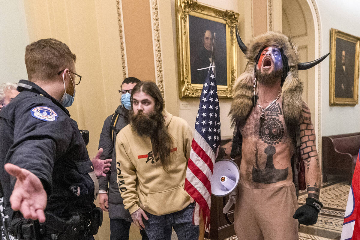 Supporters of President Donald Trump, including Jacob Chansley, right with fur hat, are confron ...