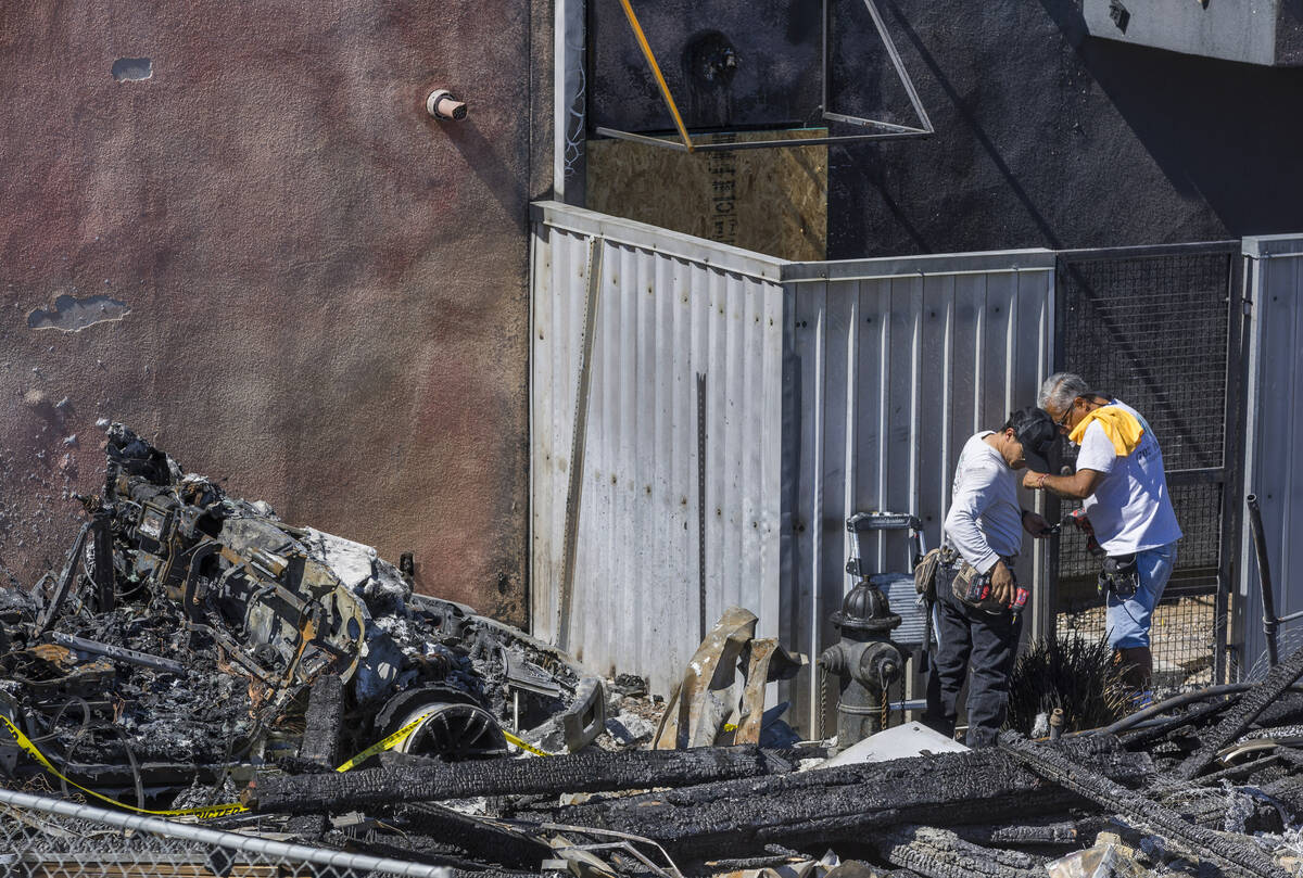 A crew works on a metal gate within the Urban Lofts Townhomes property where fire originated fr ...