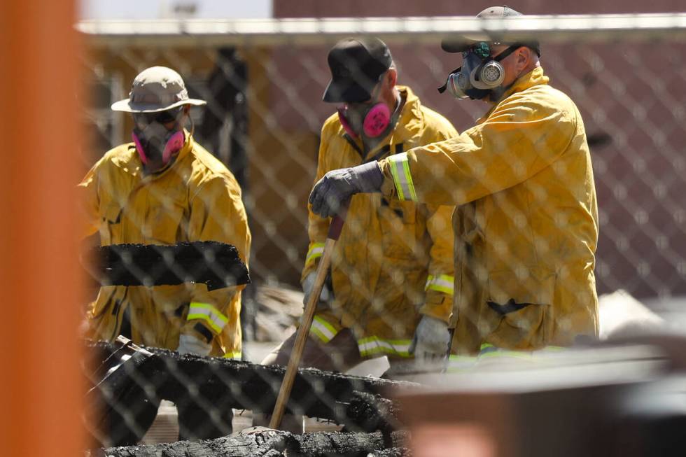 Investigators work the scene of the massive fire that torched 10 buildings and dozens of cars o ...