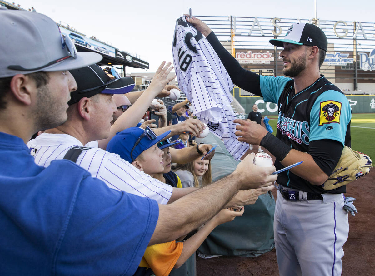 Colorado Rockies third baseman Kris Bryant, right, signs autographs during a rehab assignment w ...