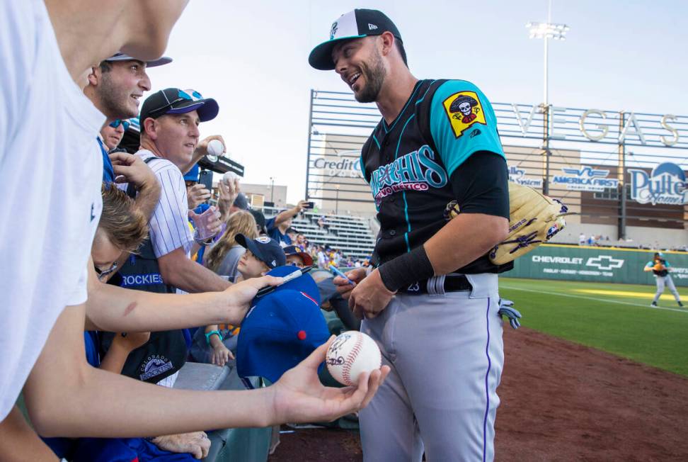 Colorado Rockies third baseman Kris Bryant, right, signs autographs during a rehab assignment w ...