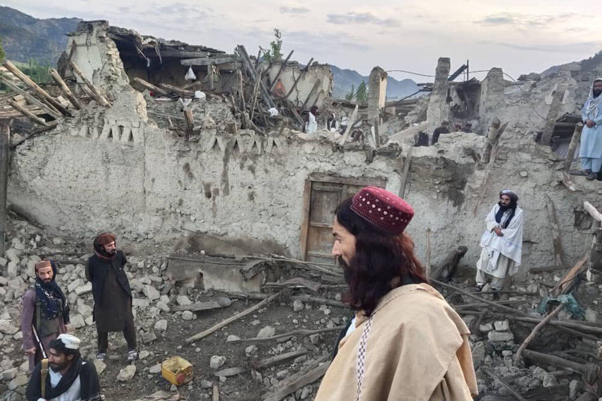 In this photo released by a state-run news agency Bakhtar, Afghans look at destruction caused b ...