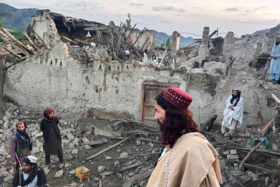 In this photo released by a state-run news agency Bakhtar, Afghans look at destruction caused b ...