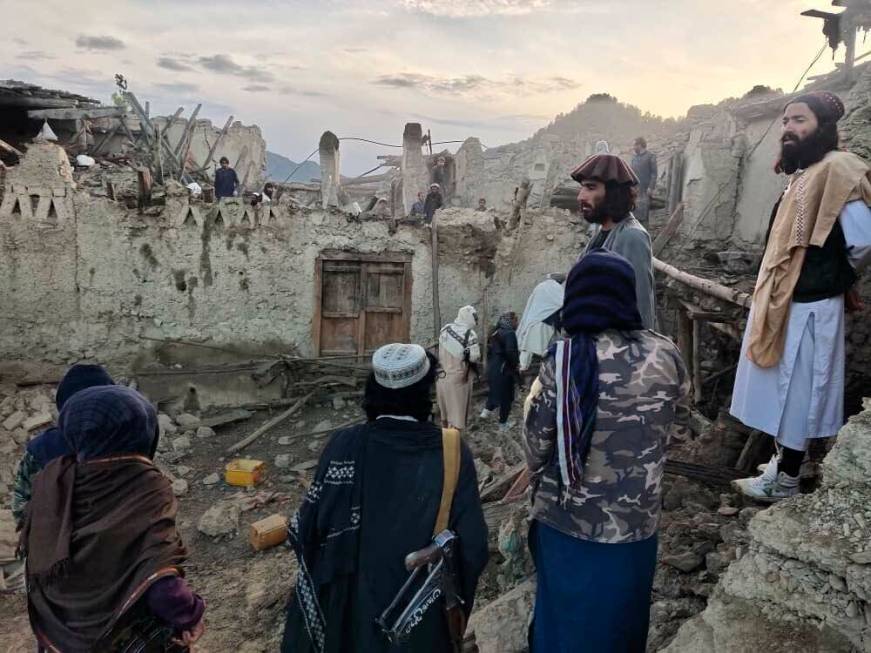 In this photo released by a state-run news agency Bakhtar, Afghans look at destruction caused b ...