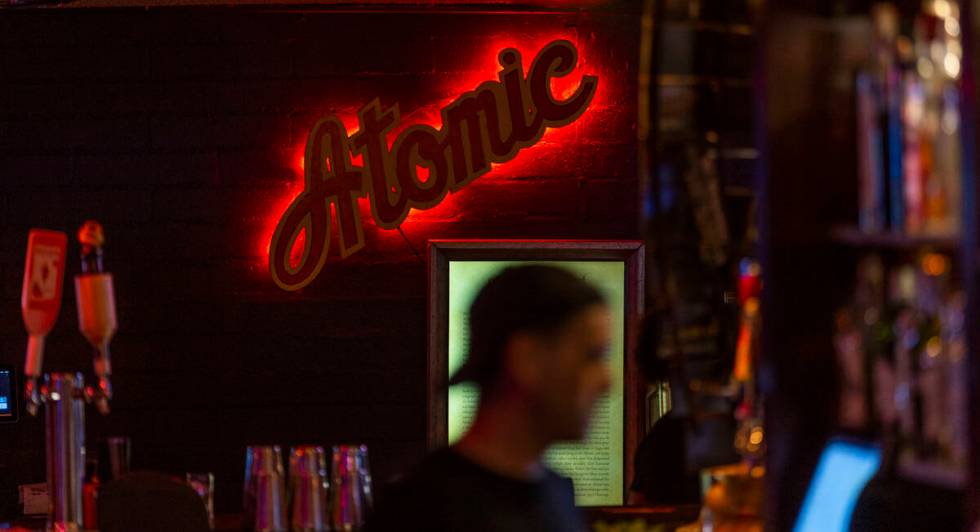 The bar lighting is dark and colorful as usual during the start of the Atomic Liquors 70th anni ...