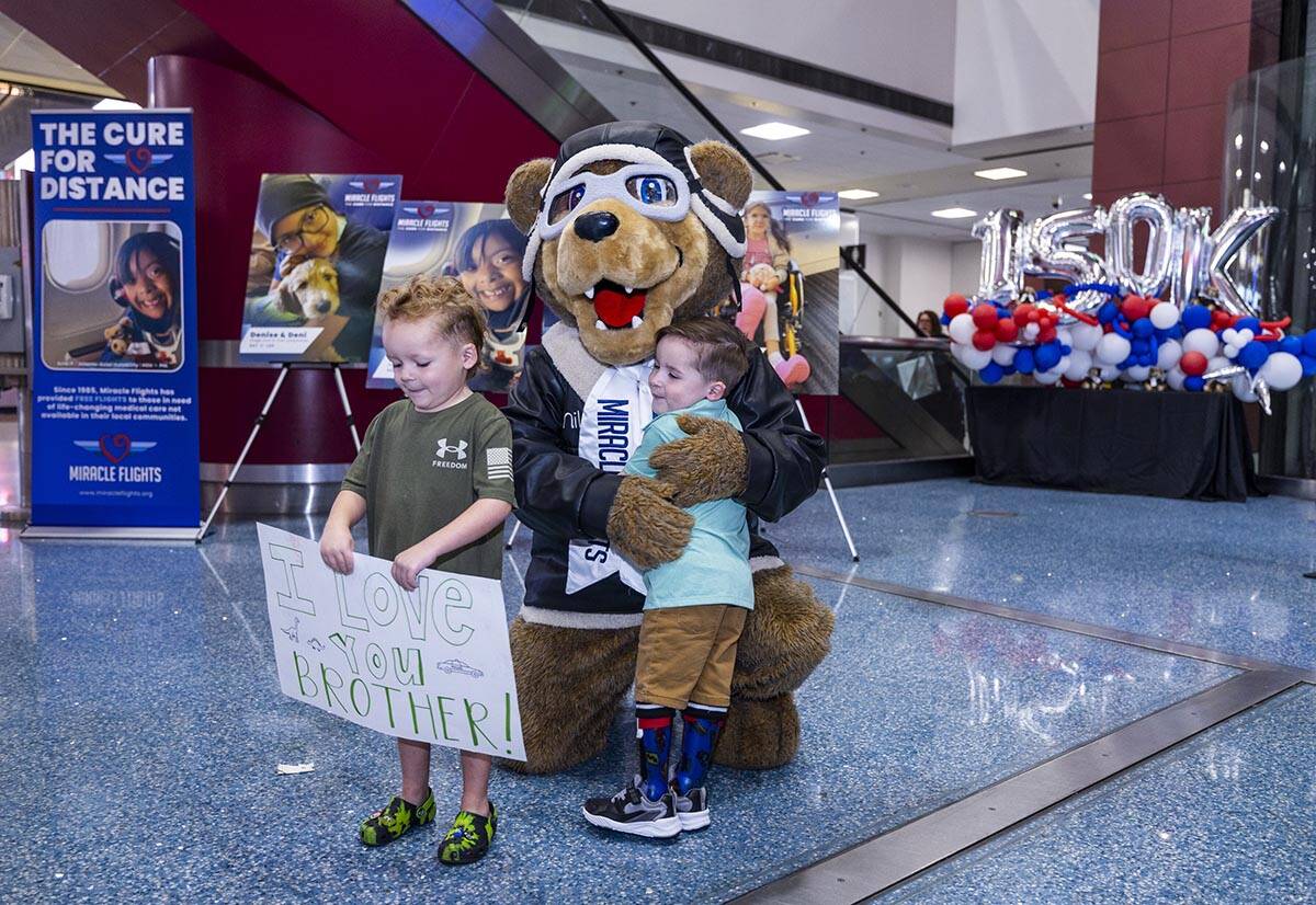 Watson Beas, 3 (center), hugs Miles the bear as his brother Beckham, 5, holds a welcome sign in ...