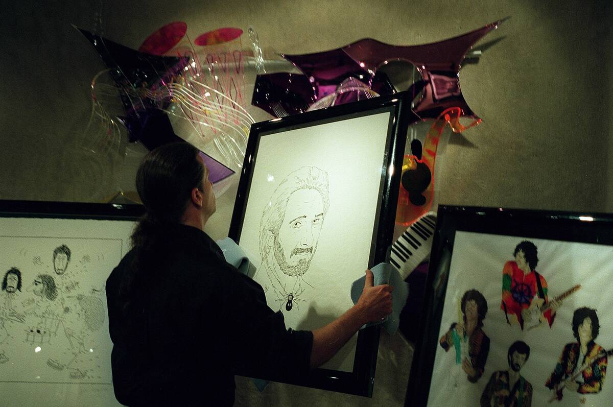 Rocky O'Nan cleans a self-portrait of John Entwistle at The Art of Music at the Desert Passage ...