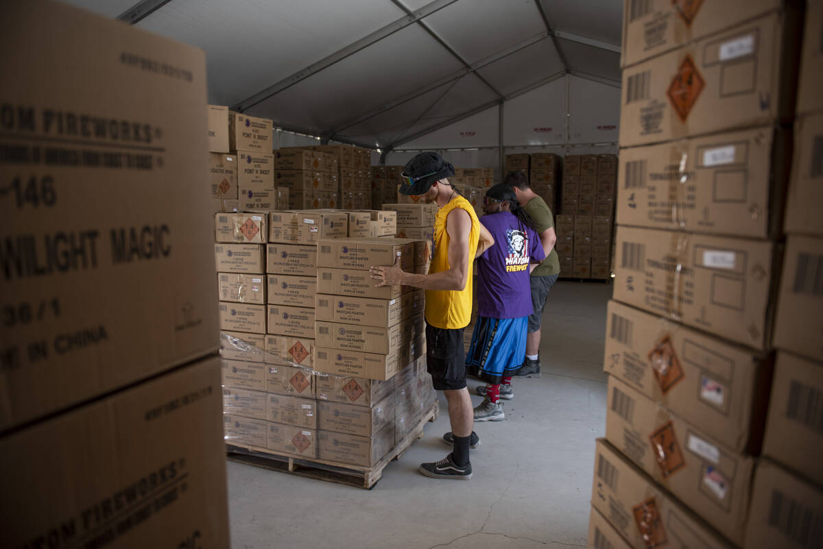 Andrew Thomas, from left, James Thomas and James Woodin, organize boxes of fireworks at the Pha ...