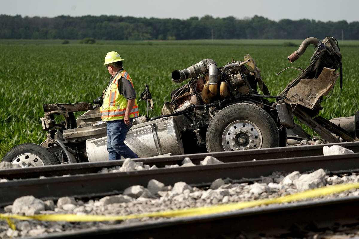 A worker looks over a dump truck that collided with an Amtrak train, causing it to derail Monda ...