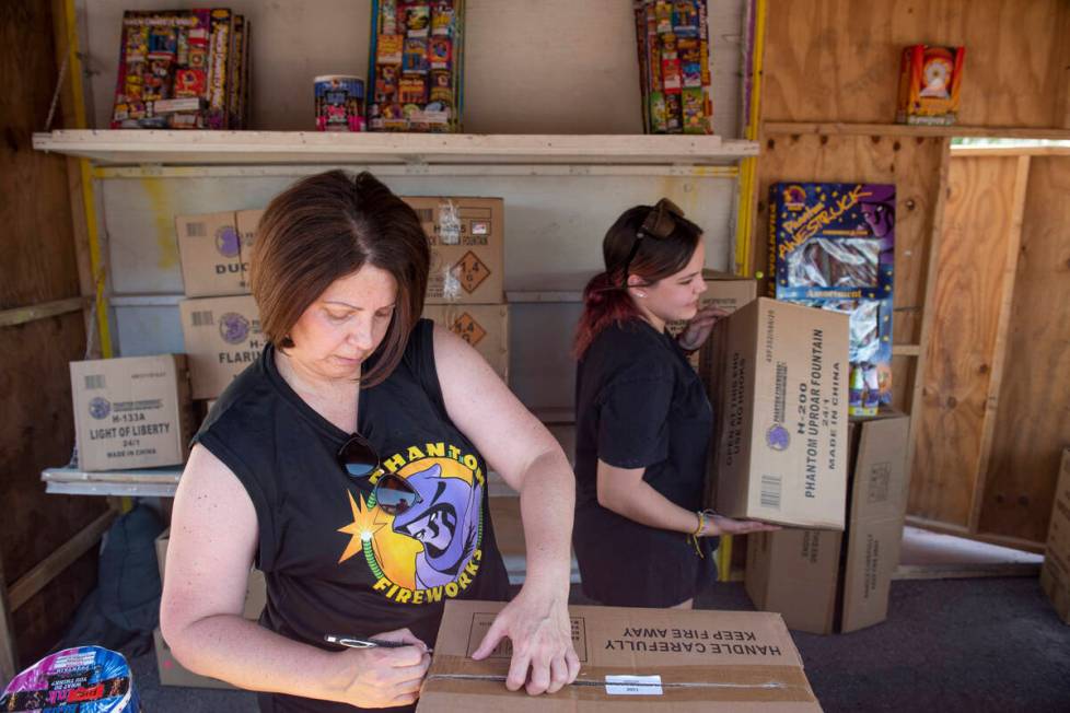 Shellie Moskos, left, and Hannah Dockery unpack and organize boxes of fireworks as they set up ...