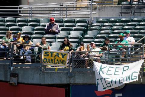 Fans sit behind a sign that reads Stay in Oakland during a baseball game between the Oakland At ...