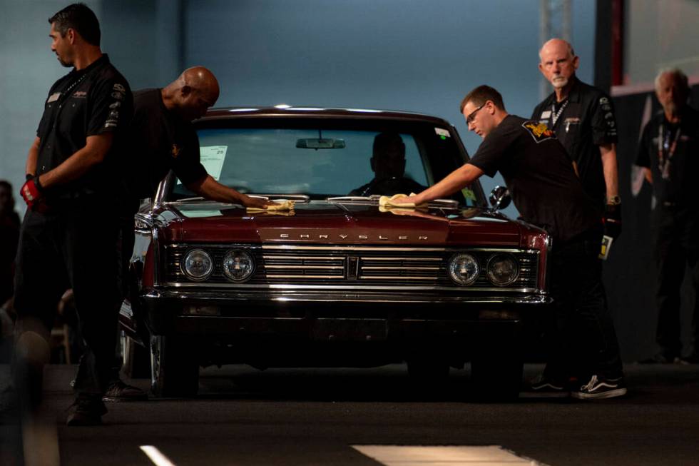 Workers give a last minute polish to a 1966 Chrysler Newport before it goes up on the auction b ...