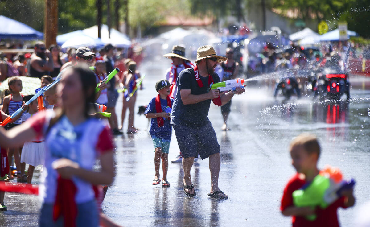 In this July 4, 2019, file photo, spectators partake in water fights during the parade at the a ...