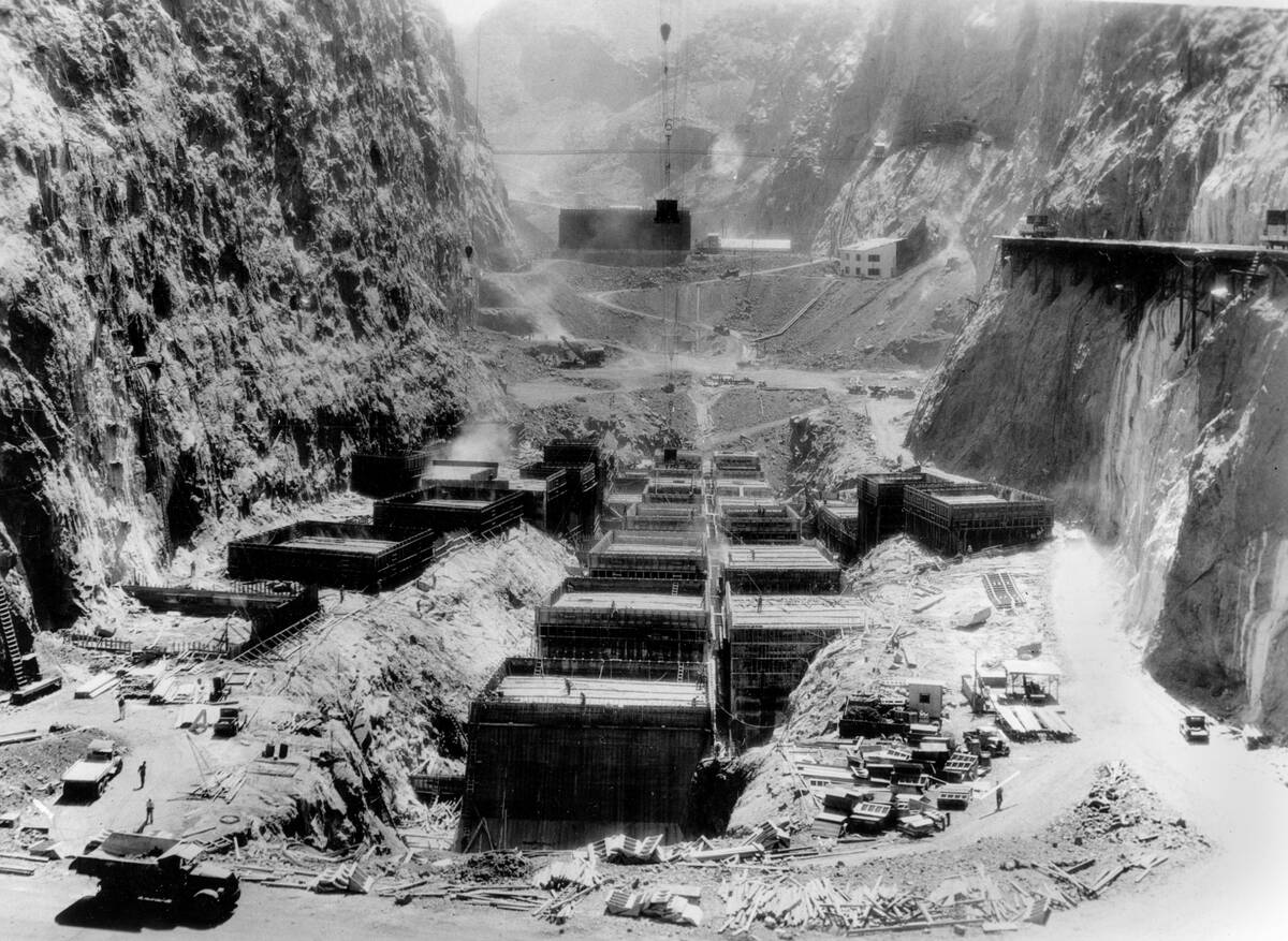 This is a downstream view of the Hoover Dam showing the immense concrete blocks rising from the ...