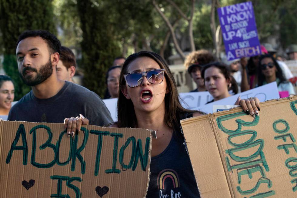 Chelsea Chavez, of Las Vegas, carries signs reading “abortion is healthcare” and ...