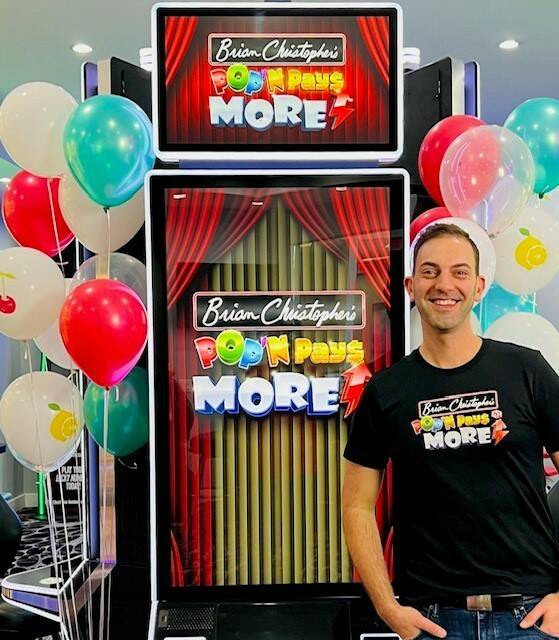 Brian Christopher poses with Pop'N Pays More, a slot machine featuring his likeness. (Photo cou ...