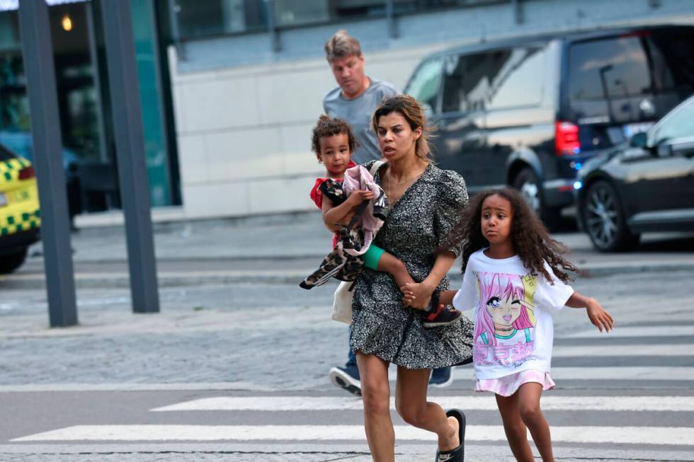 A woman and children flee the Field's shopping center after a shooting, in Copenhagen, Denmark, ...