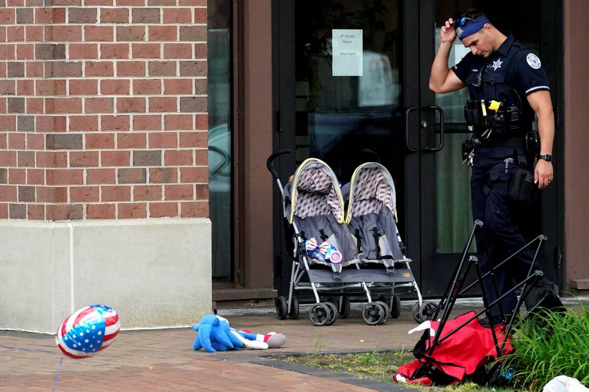 A police officer reacts as he walks in downtown Highland Park, a suburb of Chicago, Monday, Jul ...