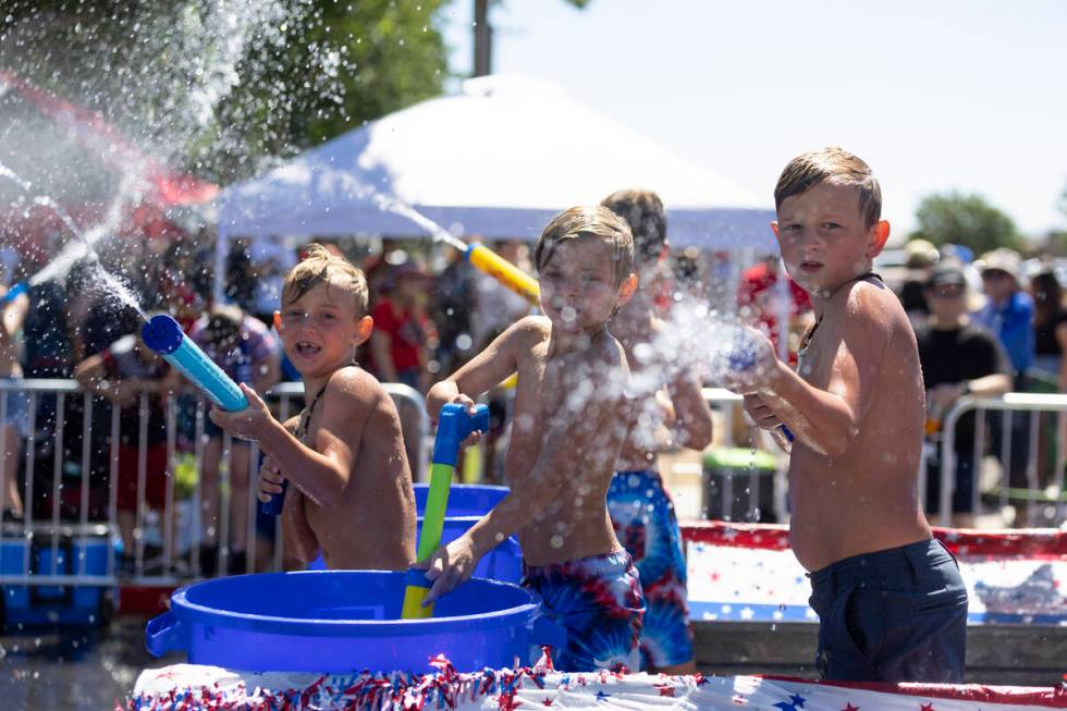 Children spray water on the crowd from a moving truck in the water zone following the Boulder C ...