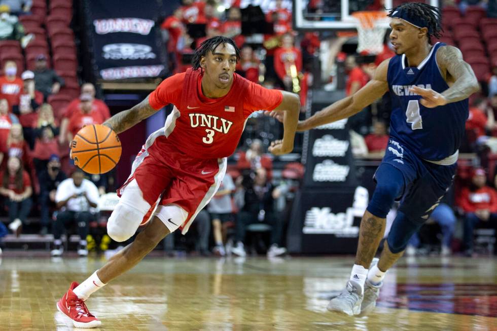 UNLV Rebels forward Donovan Williams (3) dribbles up the court while Nevada Wolf Pack guard Des ...