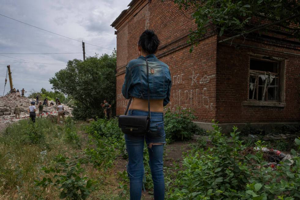 A woman looks at rescue workers at scene in the aftermath of a Russian rocket that hit an apart ...