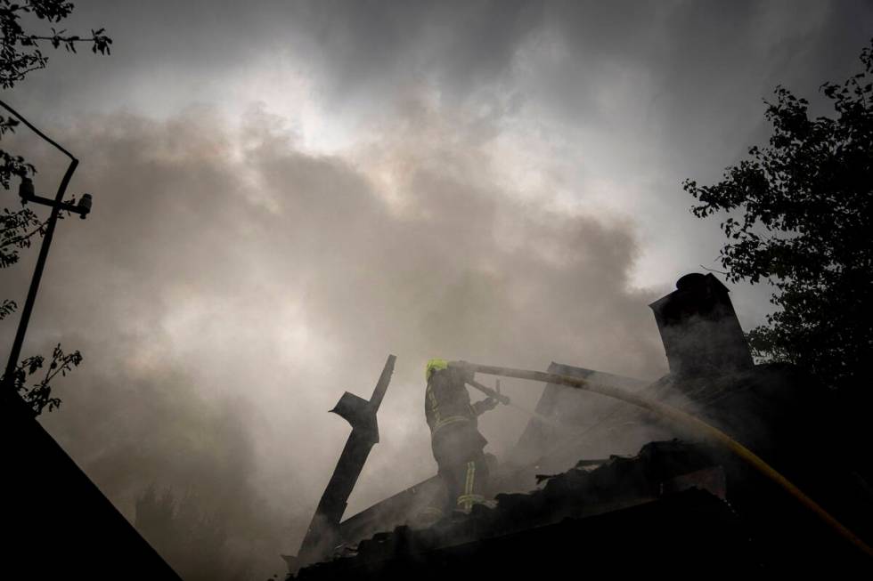 A rescue worker puts out the fire on a destroyed house after a Russian attack in a residential ...