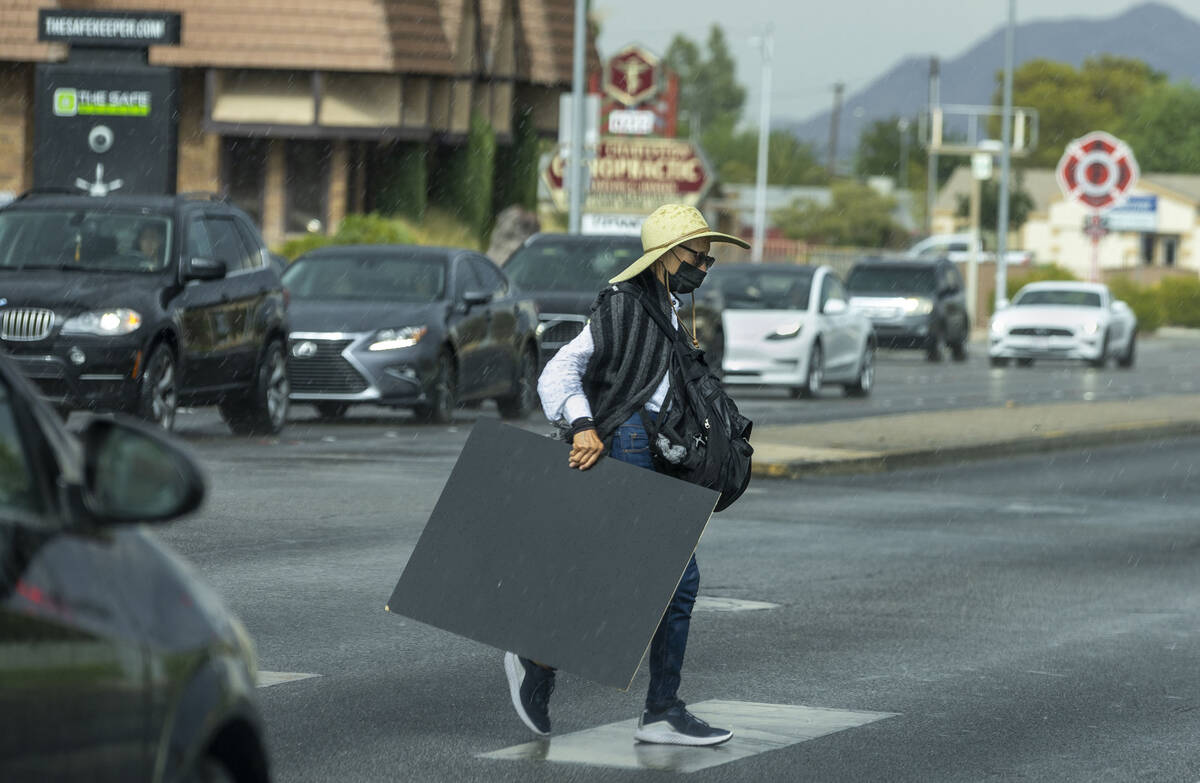 A person crosses West Charleston Boulevard as rain moves through the valley on Thursday, July 1 ...