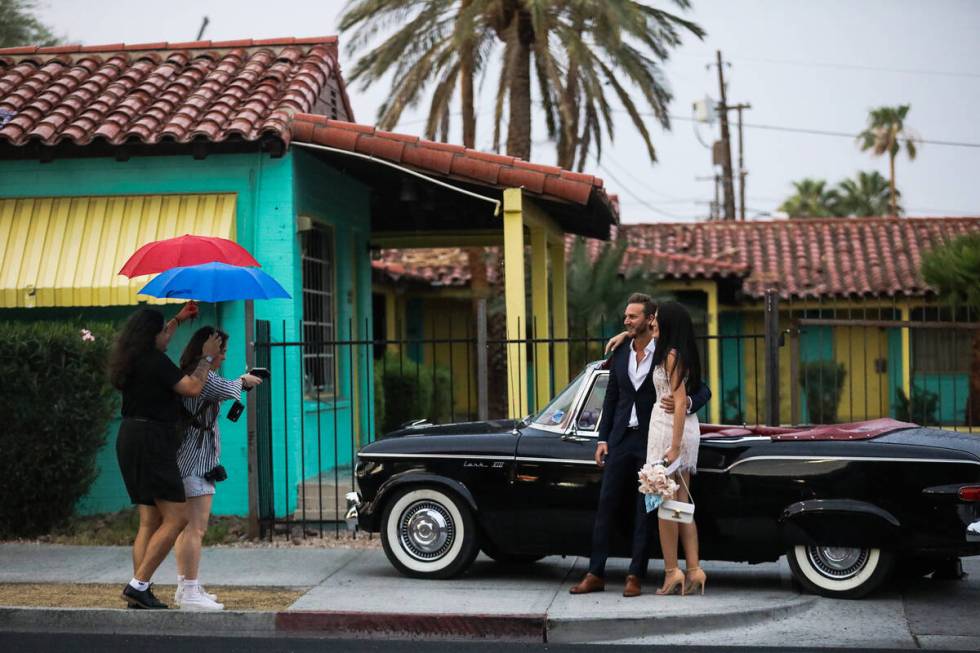 Photographer Andi Artigue, with assistance from George Foskaris holding an umbrella, takes phot ...