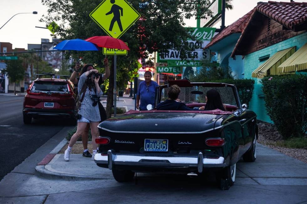 Photographer Andi Artigue, with assistance from George Foskaris holding an umbrella, takes phot ...