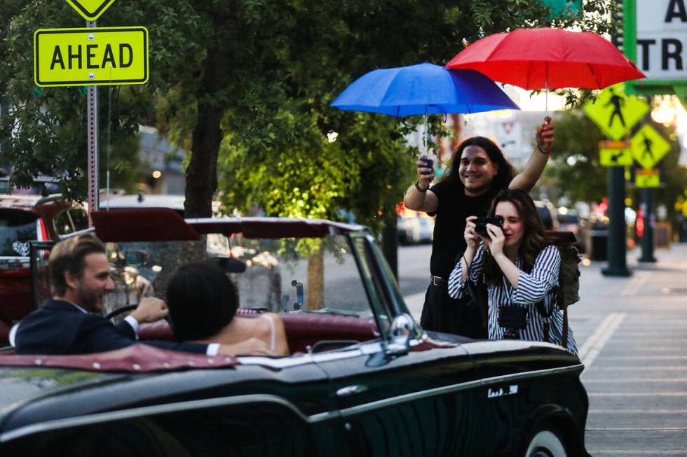 Photographer Andi Artigue, with assistance from George Foskaris holding an umbrella, takes phot ...