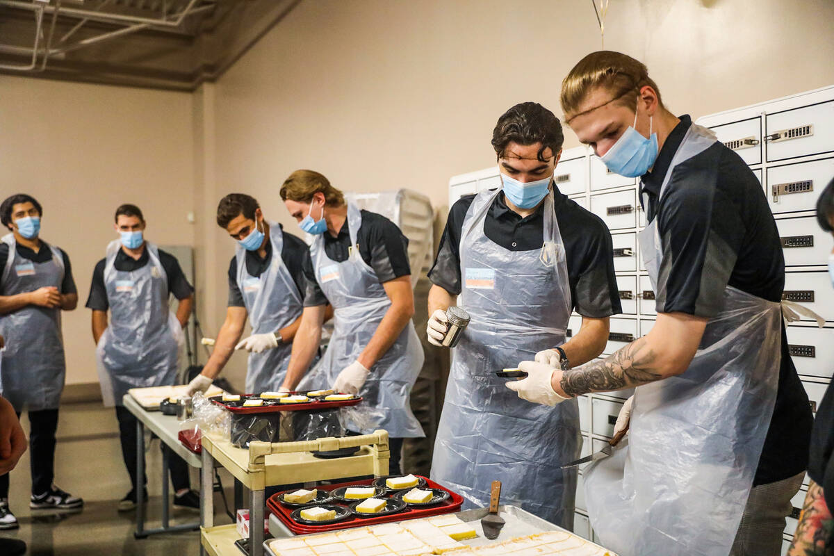 Golden Knights prospects, Daniil Chayka, far right, and Artur Cholach, left, prepare desserts a ...