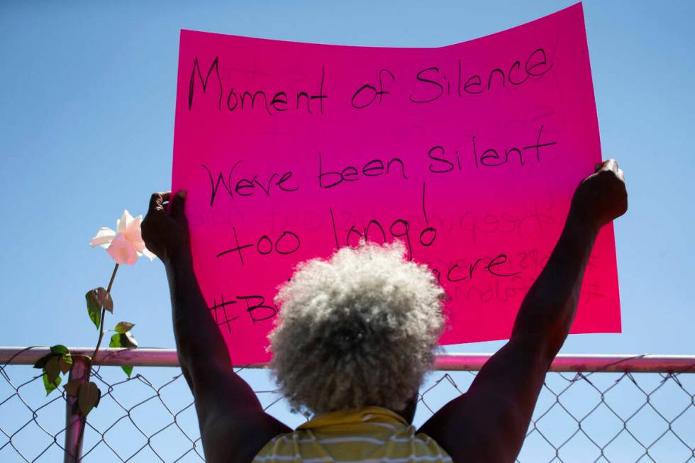 Cariol Horne, 54, holds up a sign as she stands outside the fenced-off parking lot outside Tops ...