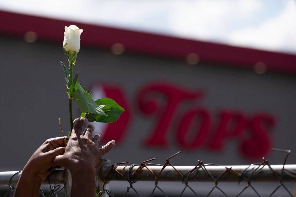 Cariol Horne, 54, places a rose on the fence outside the Tops Friendly Market on Thursday, July ...