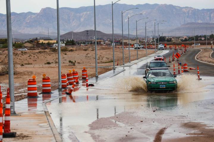 Cars drive through a flooded road on Silverado Ranch Boulevard in Las Vegas, Monday, July 25, 2 ...