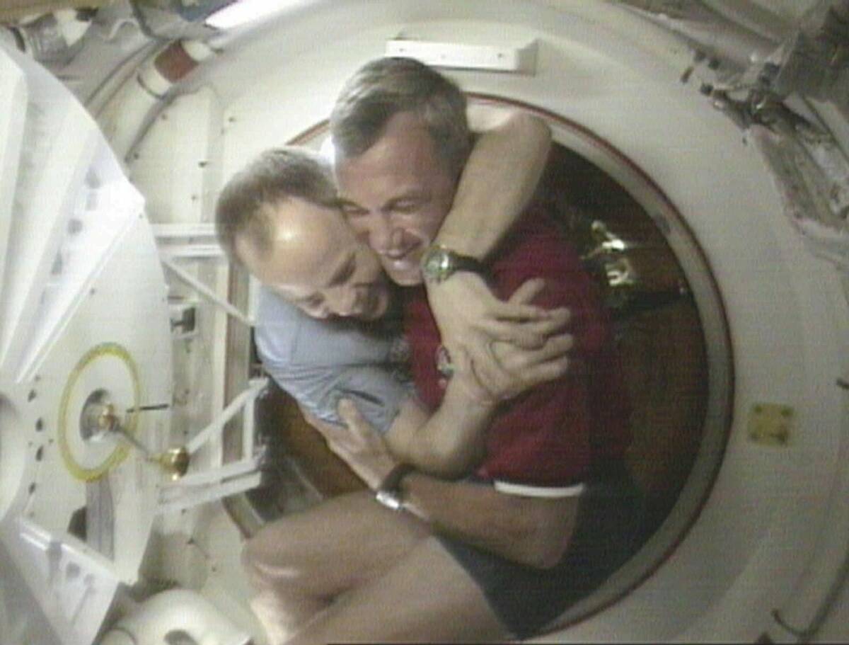 FILE - Shuttle Commander Terrence Wilcutt, right, and Mir Commander Anatoly Solovyev, left, hug ...