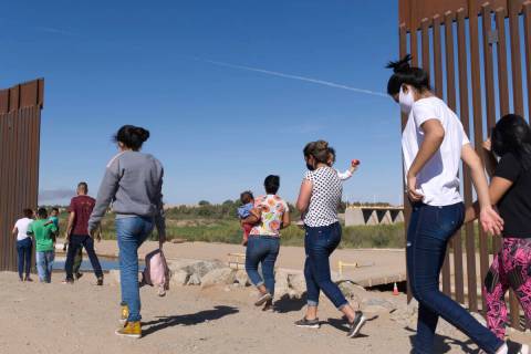 FILE - A group of Brazilian migrants make their way around a gap in the U.S.-Mexico border in Y ...