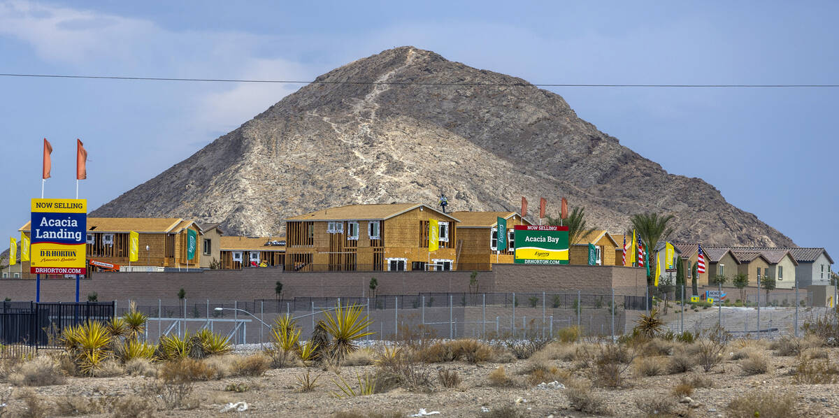 A roofer works on new home construction at Acacia Landing with Lone Mountain behind on Wednesda ...