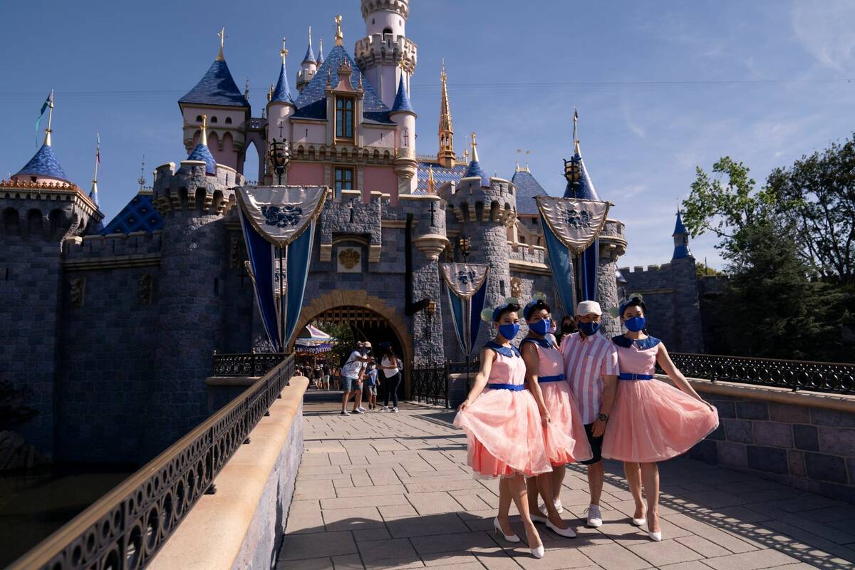 Visitors take pictures in front of the Sleeping Beauty Castle at Disneyland in Anaheim, Calif., ...