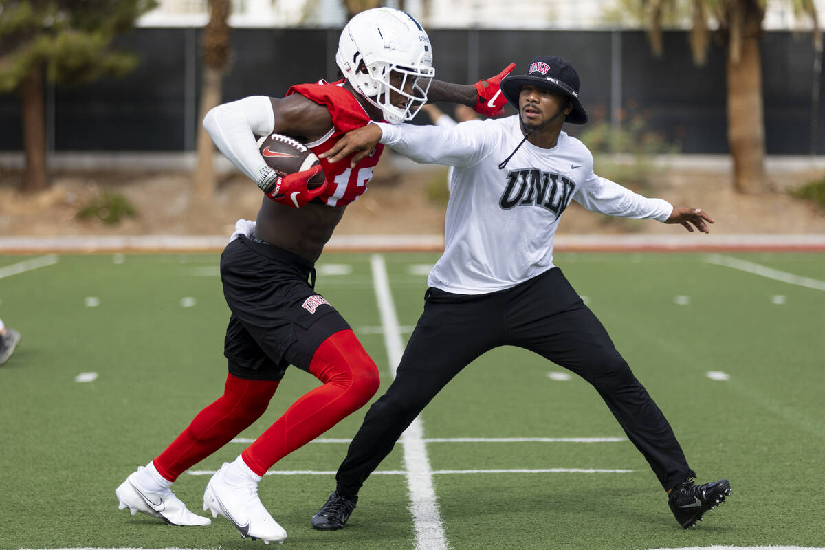 UNLV's Jordan Jakes (17) runs the ball after a catch as coach Jonathan Krause reaches for the b ...