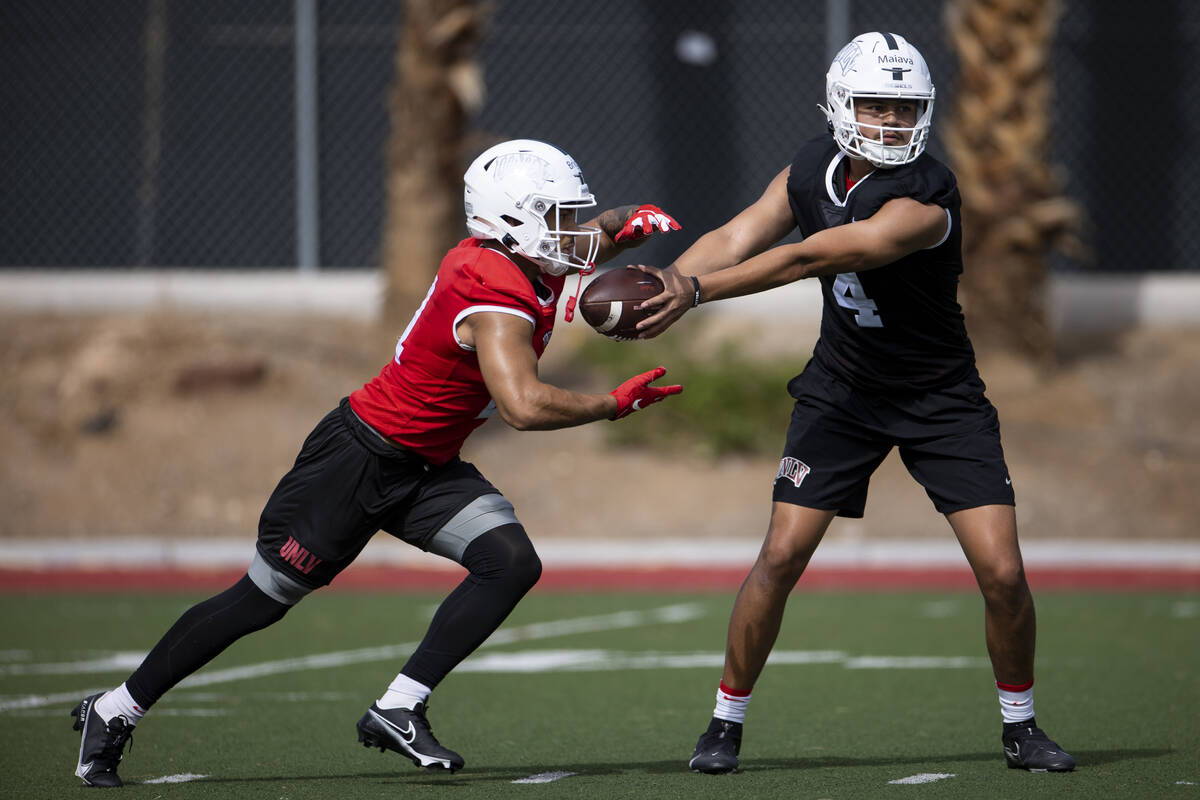 UNLV's Jayden Maiava (4), right hands off the ball to Spencer Briggs (21) during a team footbal ...