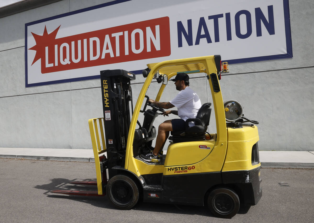 Franky Perez, owner of Liquidation Nation, a furniture store, drives passing a sign at his ware ...